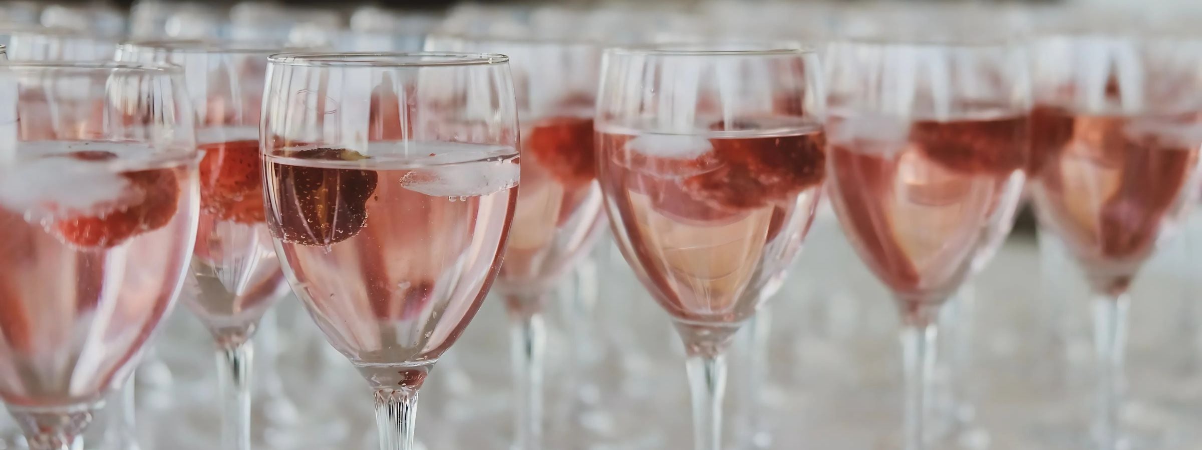 Chilled rosé wine bottles and glasses on a picnic blanket with strawberries and light snacks