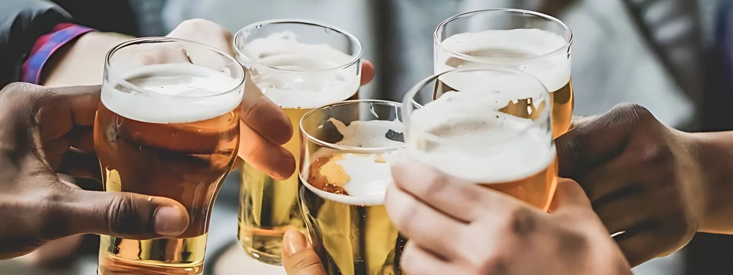 Bottles and cans of beer and cider arranged with snacks on an outdoor table