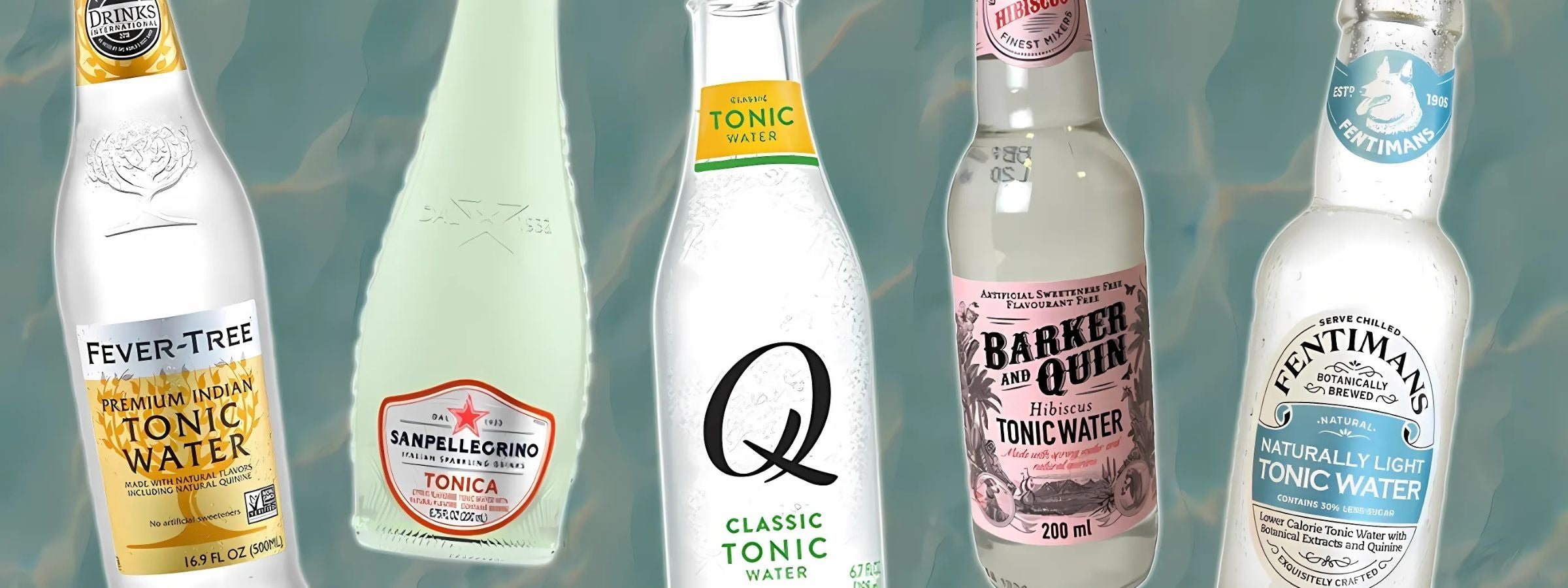 Selection of tonic water bottles in various flavours with citrus garnishes and cocktail glassware