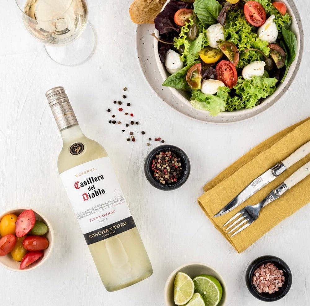 Casillero del Diablo Pinot Grigio 75cl bottle with citrus and chilled wine glass on light wood table