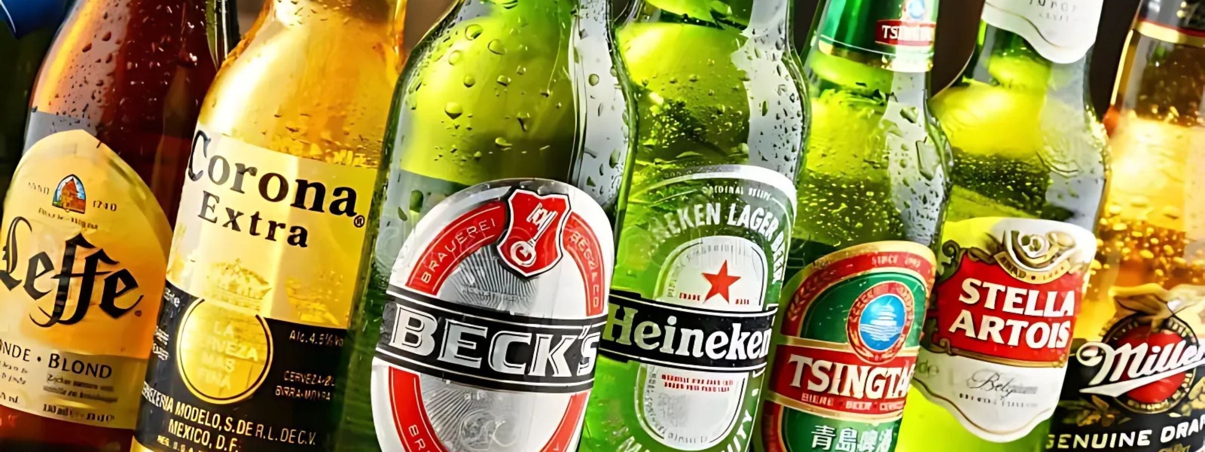 Assorted lager bottles and cans chilled in ice bucket with beer glasses and salty snacks
